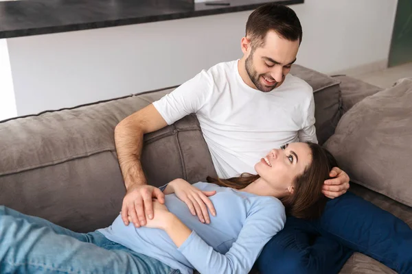 Lycklig ung gravid par koppla av på en soffa — Stockfoto