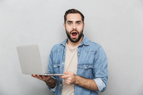 Geschokt jonge man dragen shirt geïsoleerd over Gray — Stockfoto