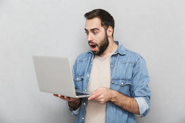 Joven impactado llevando camisa aislada sobre gris — Foto de Stock