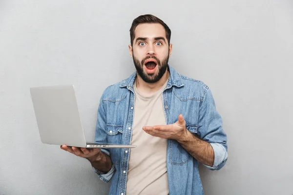 Joven impactado llevando camisa aislada sobre gris — Foto de Stock