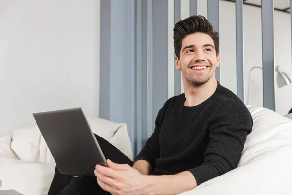 ラップトップコンピュータを使用して屋内で自宅で幸せなハンサムな若者. — ストック写真