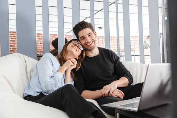 Šťastný mladý milující pár doma v interiérech s přenosným počítačem. — Stock fotografie