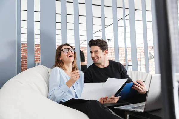Feliz joven pareja amorosa en casa en el interior utilizando el ordenador portátil de trabajo con documentos . — Foto de Stock