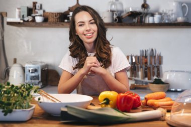Güzel genç kadın apron pişirme sebze giyiyor