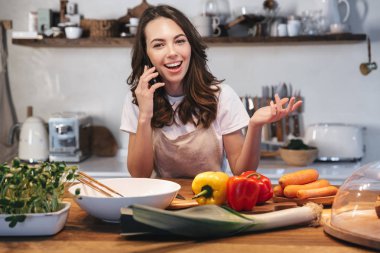 Güzel genç kadın apron pişirme sebze giyiyor