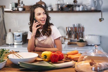 Güzel genç kadın apron pişirme sebze giyiyor