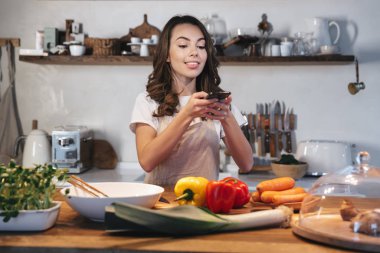 Güzel genç kadın apron pişirme sebze giyiyor