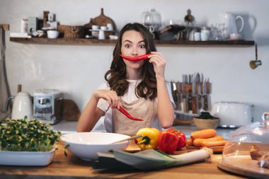 Güzel genç kadın apron pişirme sebze giyiyor