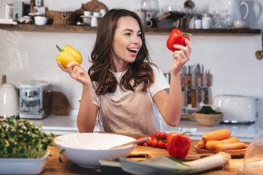 Güzel genç kadın apron pişirme sebze giyiyor