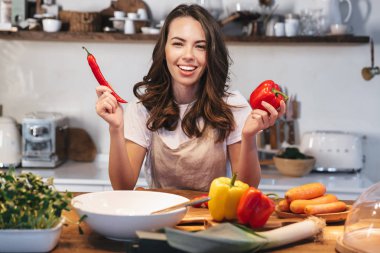 Güzel genç kadın apron pişirme sebze giyiyor