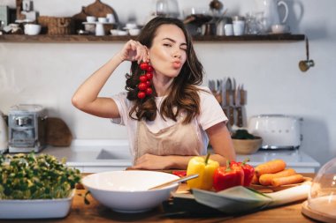 Güzel genç kadın apron pişirme sebze giyiyor