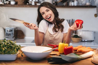 Güzel genç kadın apron pişirme sebze giyiyor