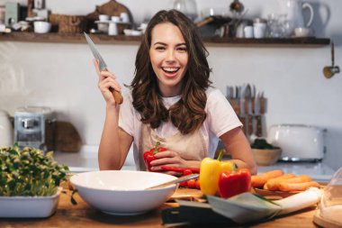 Güzel genç kadın apron pişirme sebze giyiyor