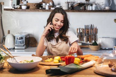 Güzel genç kadın apron pişirme sebze giyiyor