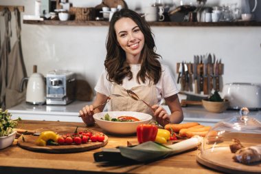 Güzel genç kadın apron pişirme sebze giyiyor