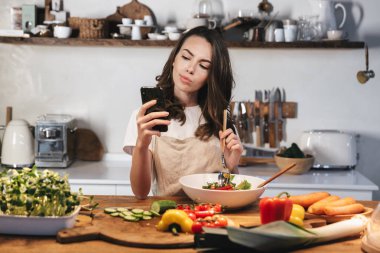 Güzel genç kadın apron pişirme sebze giyiyor