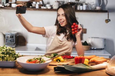Güzel genç kadın apron pişirme sebze giyiyor
