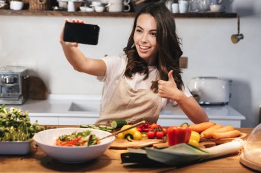 Güzel genç kadın apron pişirme sebze giyiyor