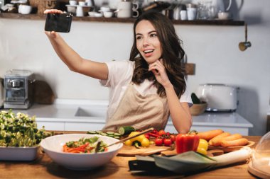 Güzel genç kadın apron pişirme sebze giyiyor