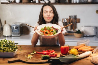 Güzel genç kadın apron pişirme sebze giyiyor