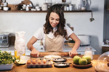 Hamur hazırlayan önlük giyen neşeli genç kadın