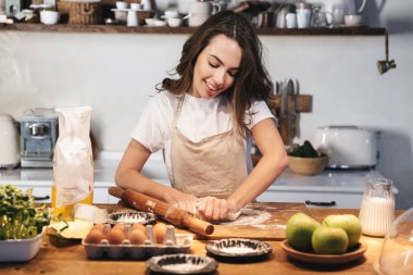 Hamur hazırlayan önlük giyen neşeli genç kadın