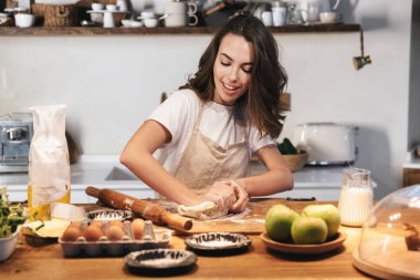 Hamur hazırlayan önlük giyen neşeli genç kadın