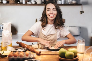 Hamur hazırlayan önlük giyen neşeli genç kadın