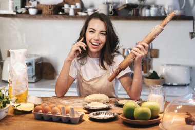 Hamur hazırlayan önlük giyen neşeli genç kadın