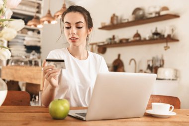 Kredi kartı tutan dizüstü bilgisayar kullanarak elma kapalı ile güzel genç öğrenci kız.