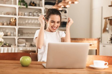 Dizüstü bilgisayar kullanarak kapalı elma ile Heyecanlı güzel genç öğrenci kız kazanan jest yapmak.