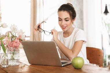 Güzel genç öğrenci kız dizüstü bilgisayar kullanarak kapalı oturan.