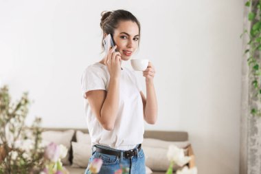 Cep telefonu ile konuşurken kapalı poz kahve içme Öğrenci kız.