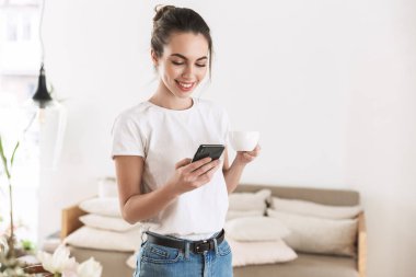 Güzel genç öğrenci kız cep telefonu ile sohbet kapalı poz kahve içme.