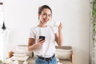 Güzel genç öğrenci kız cep telefonu ile sohbet kapalı poz kahve içme.