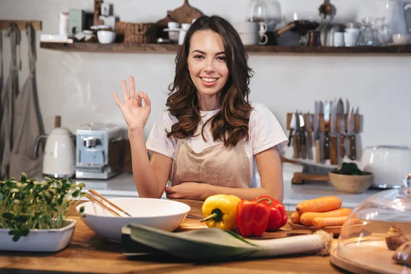 Güzel genç kadın apron pişirme sebze giyiyor