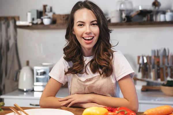 Güzel genç kadın apron pişirme sebze giyiyor