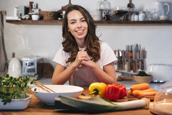 Güzel genç kadın apron pişirme sebze giyiyor