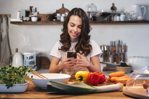 Güzel genç kadın apron pişirme sebze giyiyor