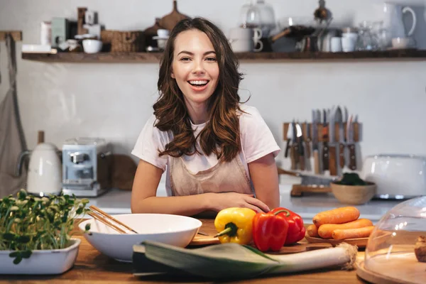 Güzel genç kadın apron pişirme sebze giyiyor