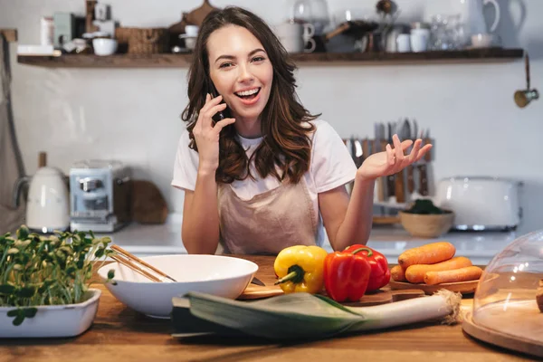 Güzel genç kadın apron pişirme sebze giyiyor