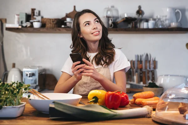 Güzel genç kadın apron pişirme sebze giyiyor