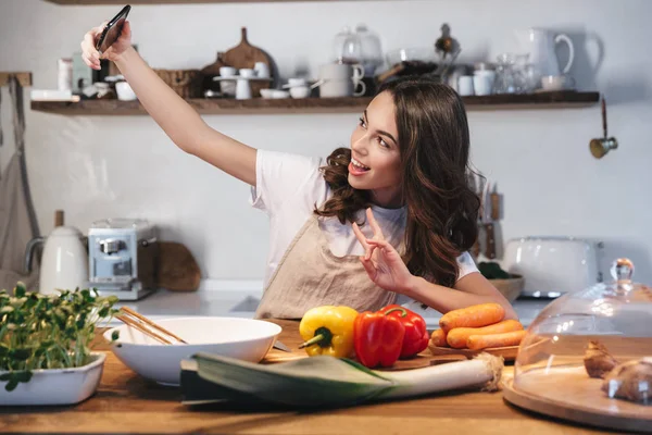 Güzel genç kadın apron pişirme sebze giyiyor