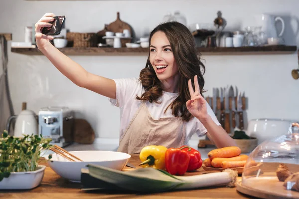 Güzel genç kadın apron pişirme sebze giyiyor