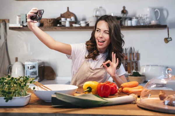 Güzel genç kadın apron pişirme sebze giyiyor