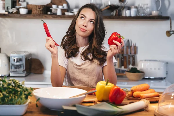 Güzel genç kadın apron pişirme sebze giyiyor