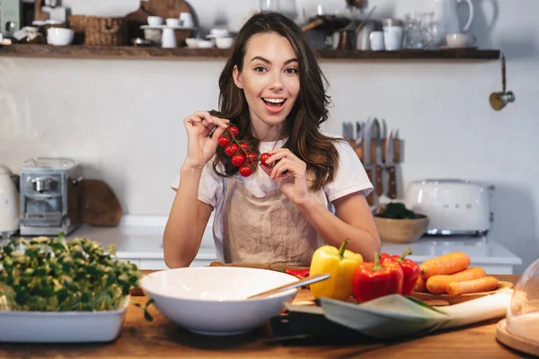 Güzel genç kadın apron pişirme sebze giyiyor — Stok fotoğraf