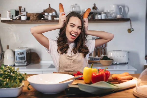 Güzel genç kadın apron pişirme sebze giyiyor — Stok fotoğraf