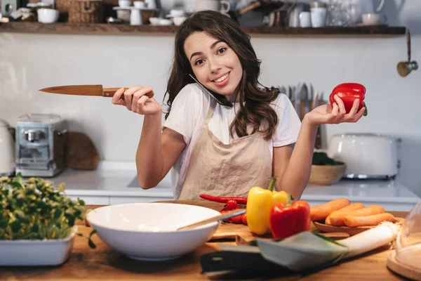 Güzel genç kadın apron pişirme sebze giyiyor — Stok fotoğraf