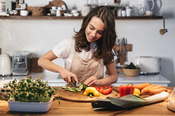 Güzel genç kadın apron pişirme sebze giyiyor — Stok fotoğraf